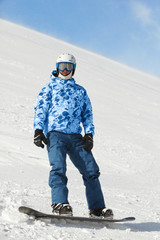 Fototapeta na wymiar Snowboarder w garniturze i kasku narciarskim stoi na snowboardzie