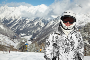 Fototapeta na wymiar Młoda kobieta w garnitur i kask narciarski stoi przed górach