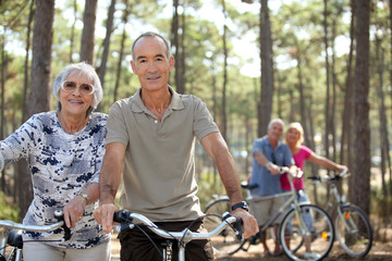 Fototapeta premium four senior people doing bike in a pine forest