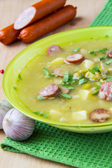 Pea soup with smoked sausages in a green plate