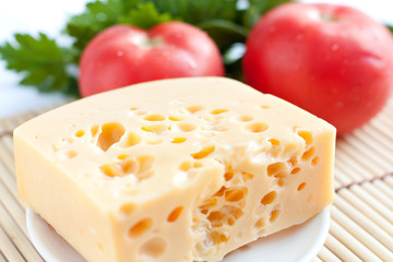 Chunk of cheese on a background of red tomatoes