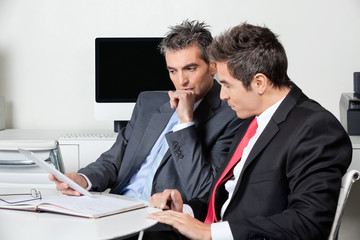 Thoughtful Businessmen Using Digital Tablet At Desk
