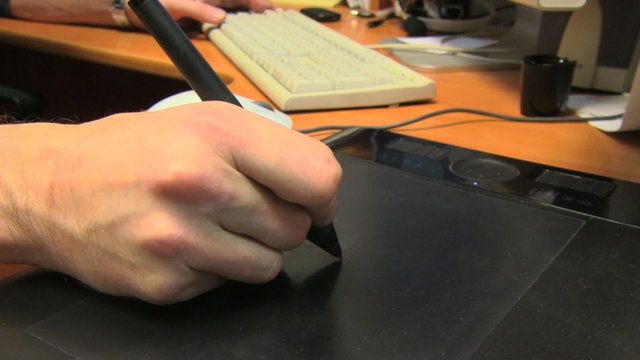 Hand of the designer with a pen on a tablet