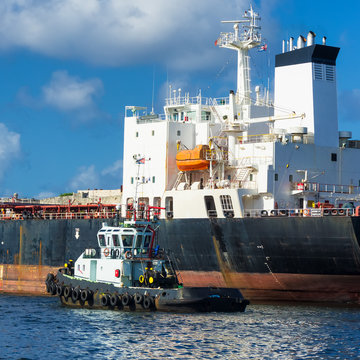 Tugboat guiding a huge cargo ship