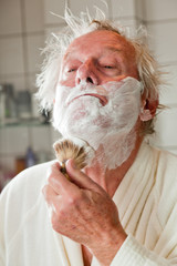 Senior man shaving his beard in bathroom.