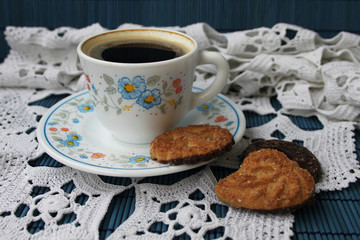 Cup of coffee and cookies on white knitting cloth