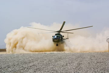 Wall murals Helicopter helicopter landing in cloud of dust of desert
