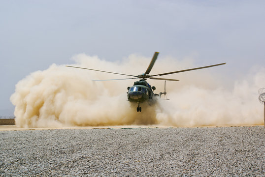 helicopter landing in cloud of dust of desert