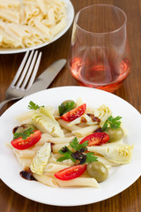salad with penne on the plate and glass of wine