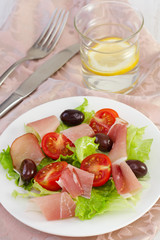 salad on the white plate and glass of water with lemon