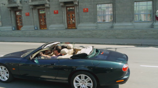 Happy young couple riding in a convertible in the city