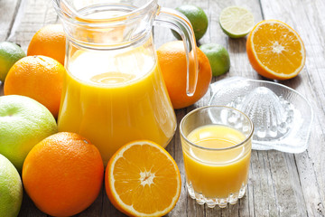 Orange juice with lime grapefruit and squeezer on wooden boards