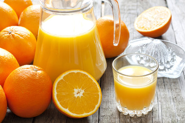 Orange juice with squeezer and jug on wooden boards
