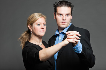 Stylish happy young couple dancing. Studio shot against grey.