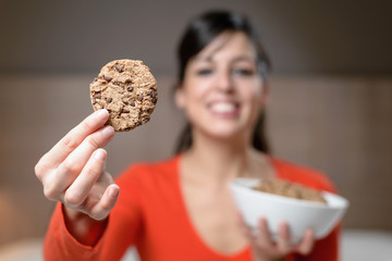 Hungry woman with cookie at night - obrazy, fototapety, plakaty