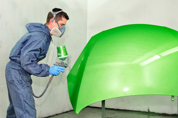 Worker painting green car bonnet.