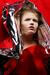 Arty portrait of a fashionable red-haired model in red with silv