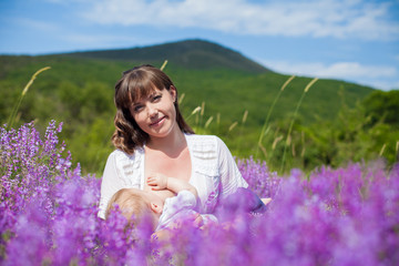 Mother breastfeeding her baby in a field of purple flowers