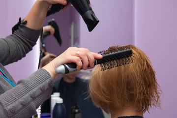 hairdresser drying woman hair in salon