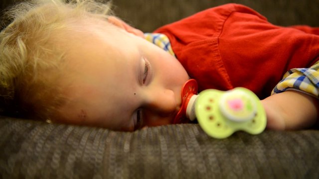 Kleinkind mit Schnuller wacht langsam auf