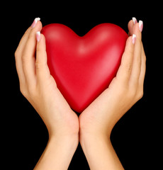 Obraz premium Red heart in woman's hands, on black background close-up