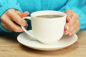 hands holding mug of hot drink, close-up