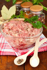 Bowl of raw ground meat with spices on wooden table