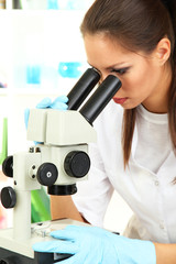 Fototapeta premium Young scientist looking into microscope in laboratory.