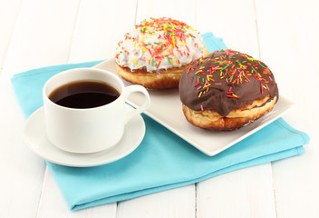 Tasty donuts on color plate on light wooden background