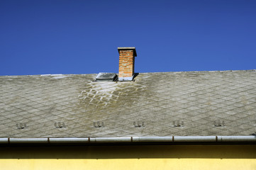 Chimneys on roof of red tiles with storm sky and clouds