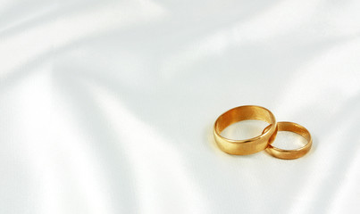 Golden wedding rings on white silk