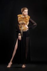 Fototapeta premium Fashion Woman in Luxury Fur Coat over Black Background posing