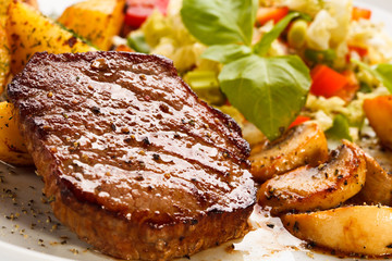 Grilled steak, baked potatoes and vegetables