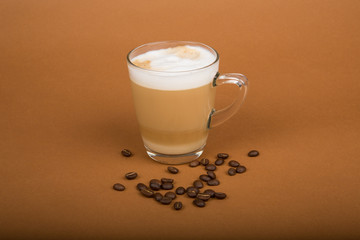 Cappuccino im Glas mit Bohnen vor weißem Hintergrund