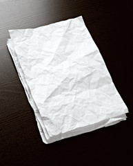 White crumpled paper on dark wood background