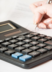 Woman's hand with a pen, calculator and the financial report 