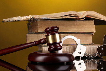 Gavel, handcuffs and.book on law on yellow background