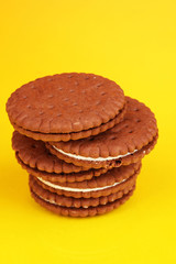 Chocolate cookies with creamy layer on yellow background