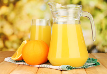 Full glass and jug of orange juice and oranges