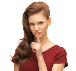 Naklejka premium teenage girl in red dress with finger on lips