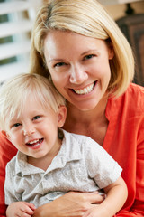 Portrait Of Mother And Son Sitting On Sofa At Home