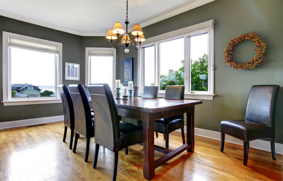 Large green dining room with leather chairs and large windows.