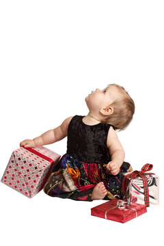 Baby In Patchwork Dress Holds Gifts And Looks Up
