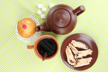 Top view of cup of tea and teapot on green tablecloths