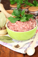 Bowl of raw ground meat with spices on wooden table