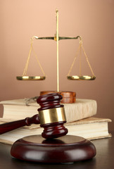 Golden scales of justice, gavel and books on brown background