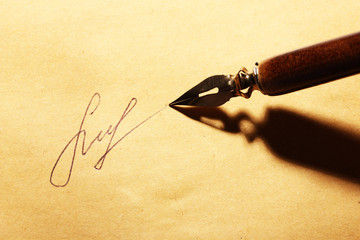 Closeup of signature (fake, not real) and ink pen, on old paper
