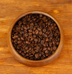 Coffee beans in wooden bowl on wooden background