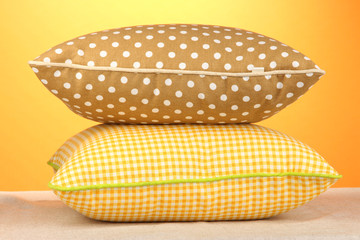 Yellow and brown bright pillows on orange background