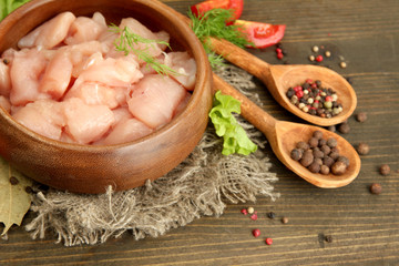 raw chicken meat in bowl, on wooden background